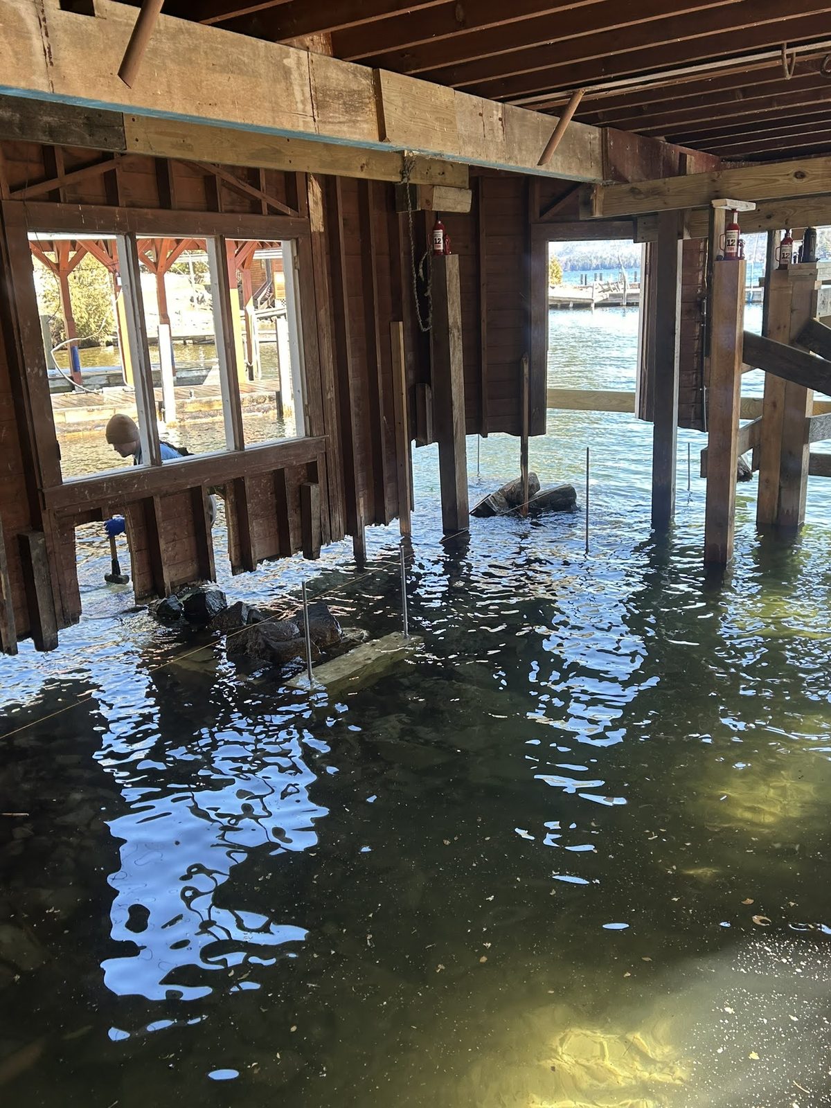 Interior of a boathouse showing timber cribs and water below