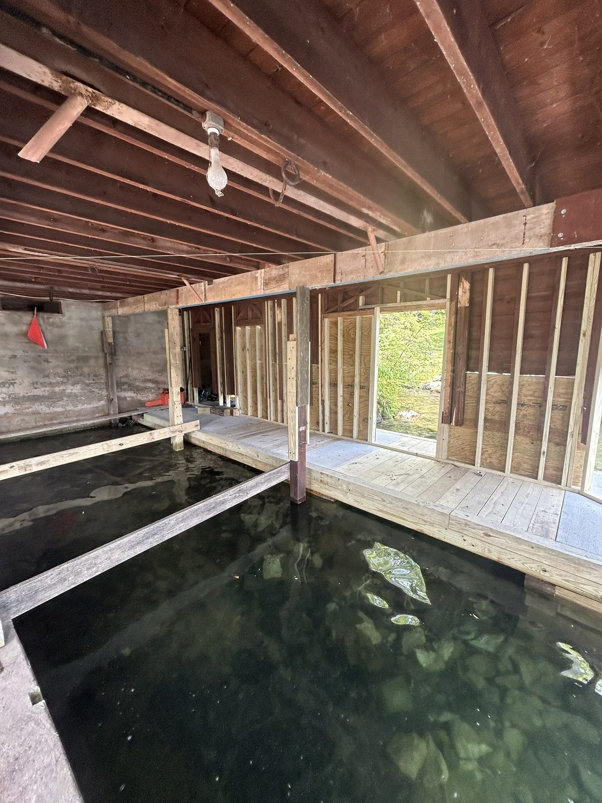 Boathouse interior mid-restoration with exposed framing over the slip