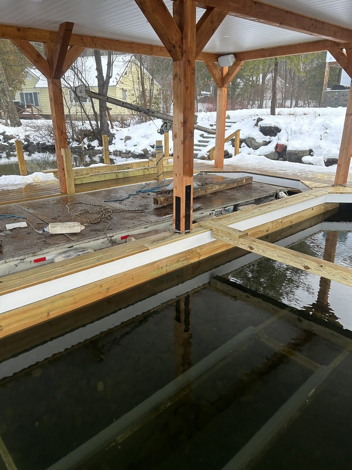 Timber-frame boathouse under construction over Lake George in winter
