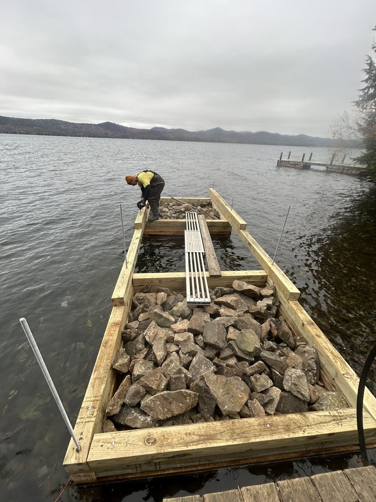 Timber crib being filled with stone at the Lake George shoreline