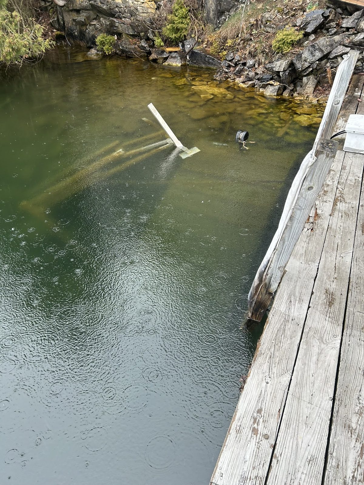 Submerged timber and hardware visible in shallow lake water