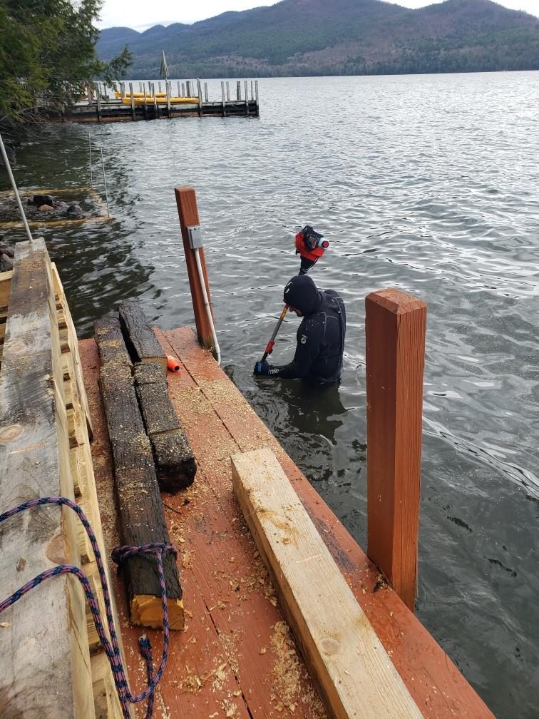 Diver in a wetsuit setting dock pilings in Lake George