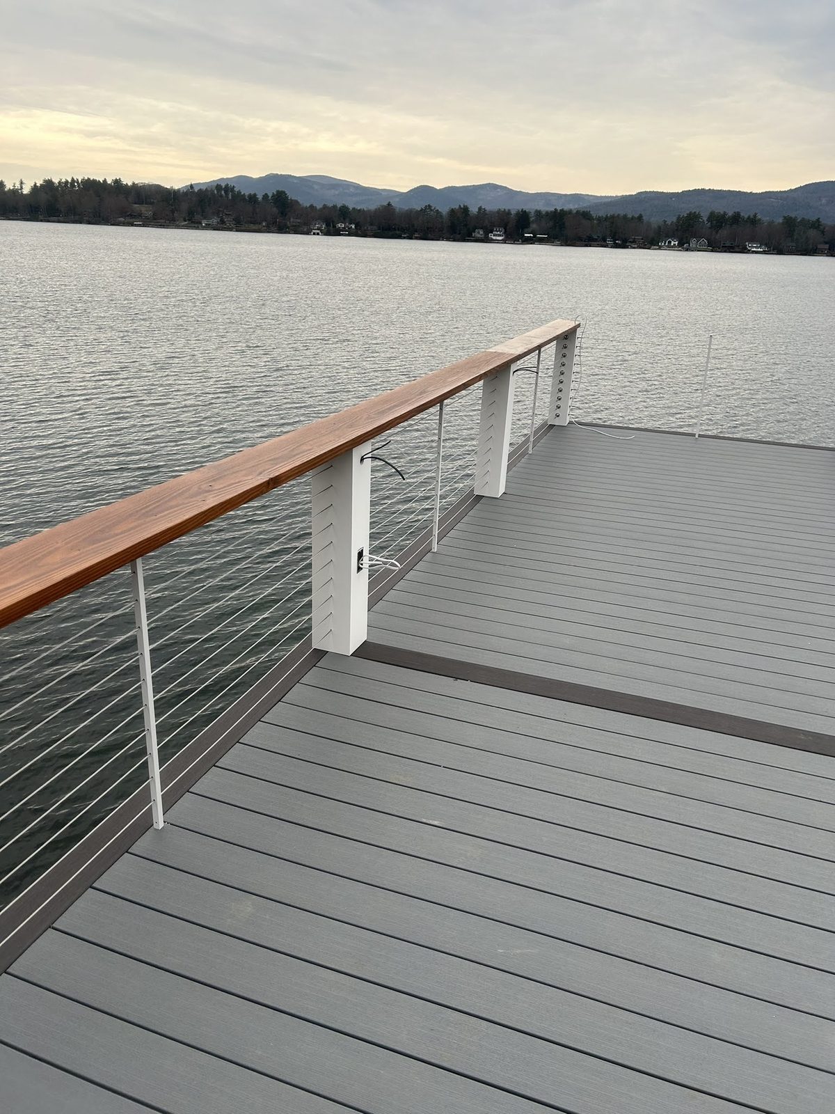 Composite dock with warm wood-topped cable railing facing the lake