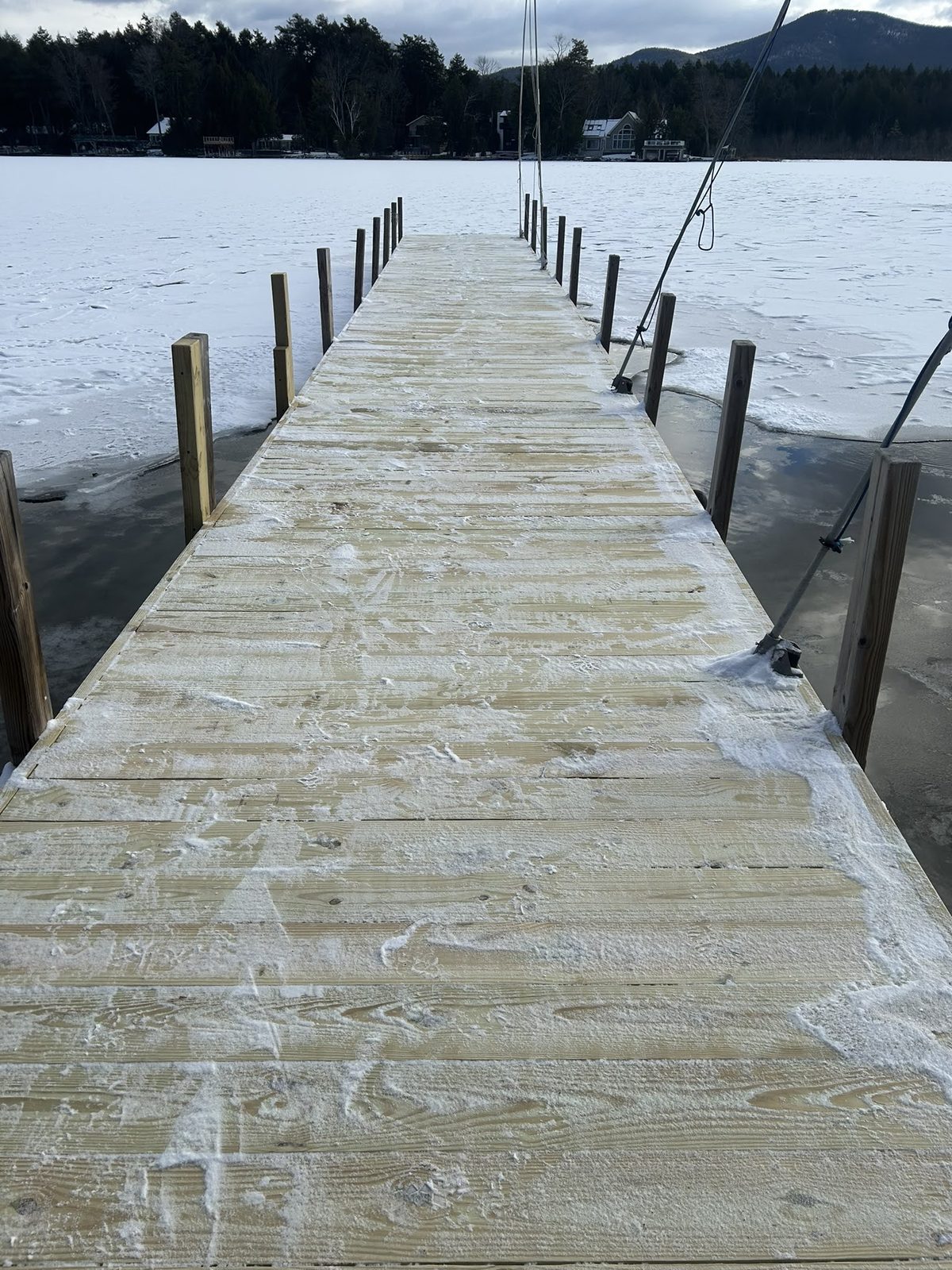 Weathered pine dock stretching into Lake George under an overcast sky