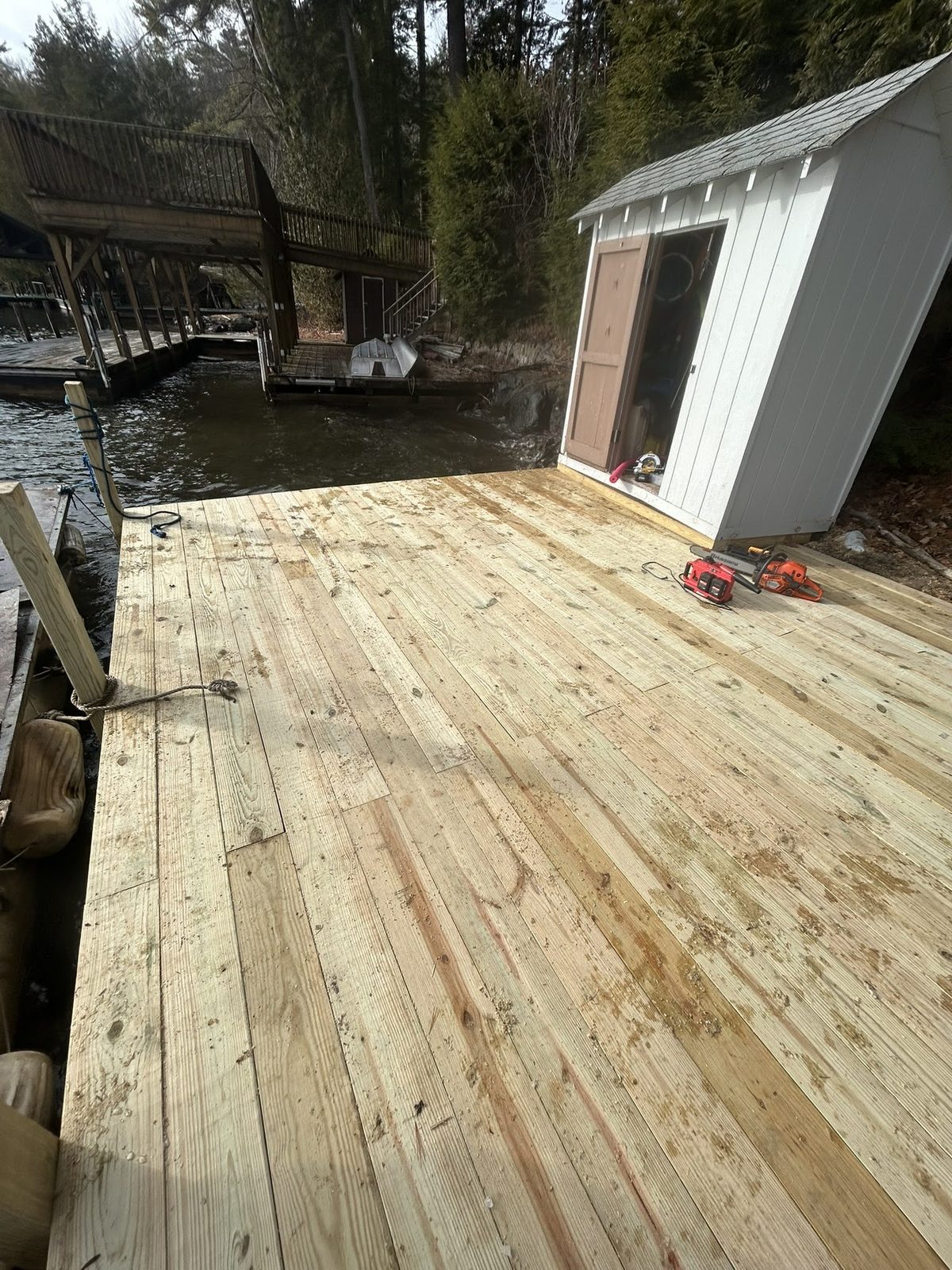 New dock decking installed beside a white Lake George boathouse