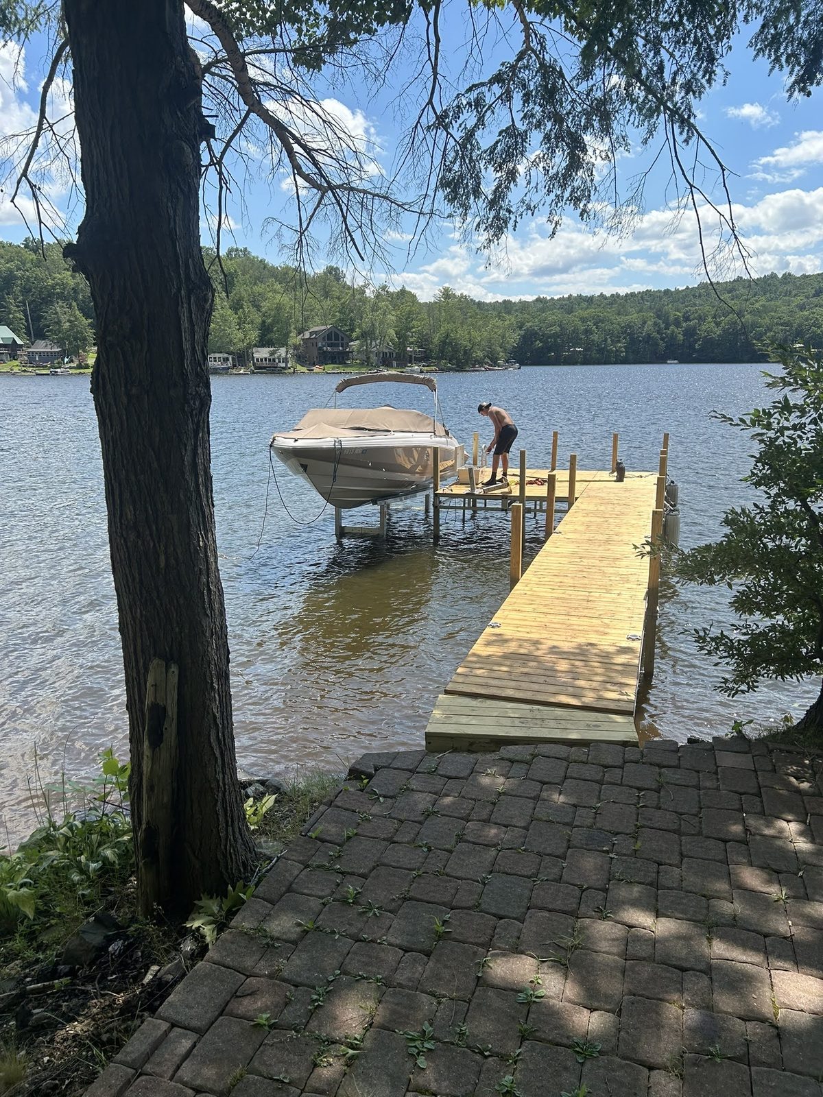 Dock and moored boat viewed from a shaded Lake George shoreline