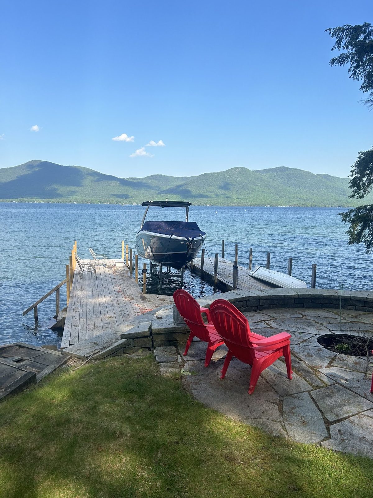Custom dock with moored boat and Adirondack chairs looking north up Lake George