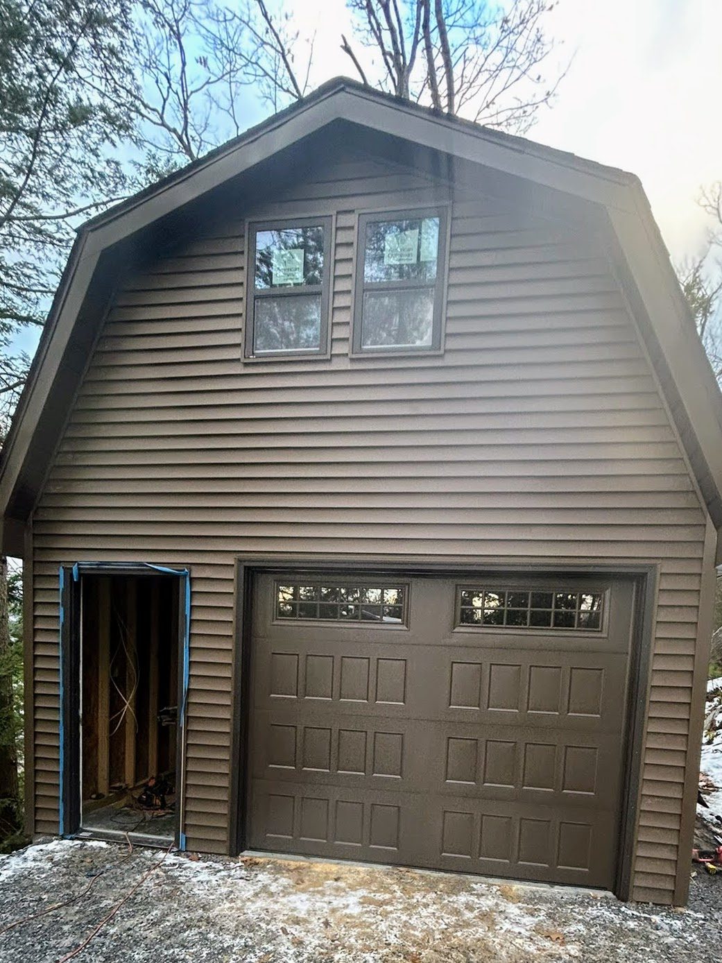 Completed gambrel-roof garage with new doors and siding