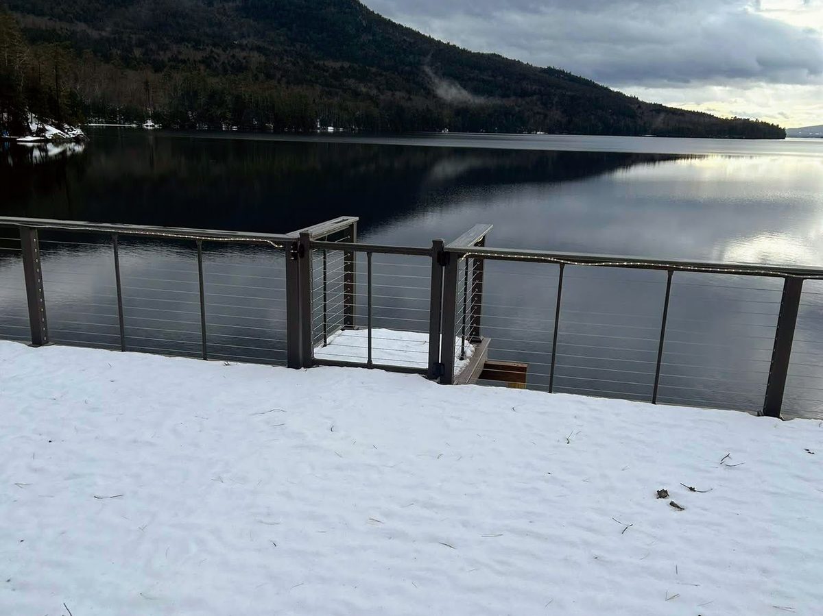 Cable railing and dock under snow with the lake beyond