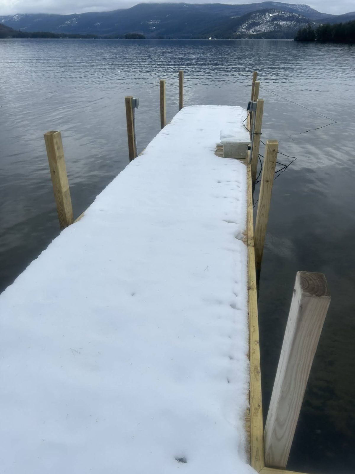 Deep snow covering a Lake George dock with pilings exposed